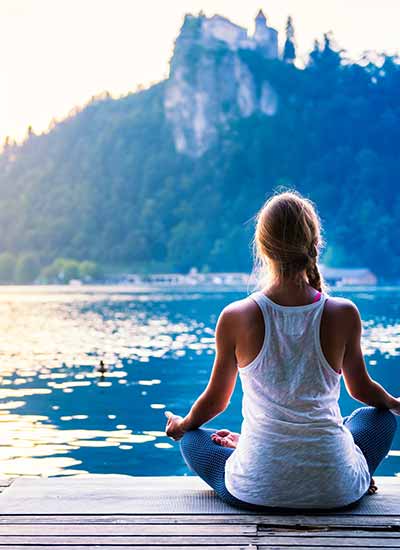 woman sitting by blue lake