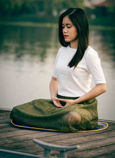 Woman meditating by water